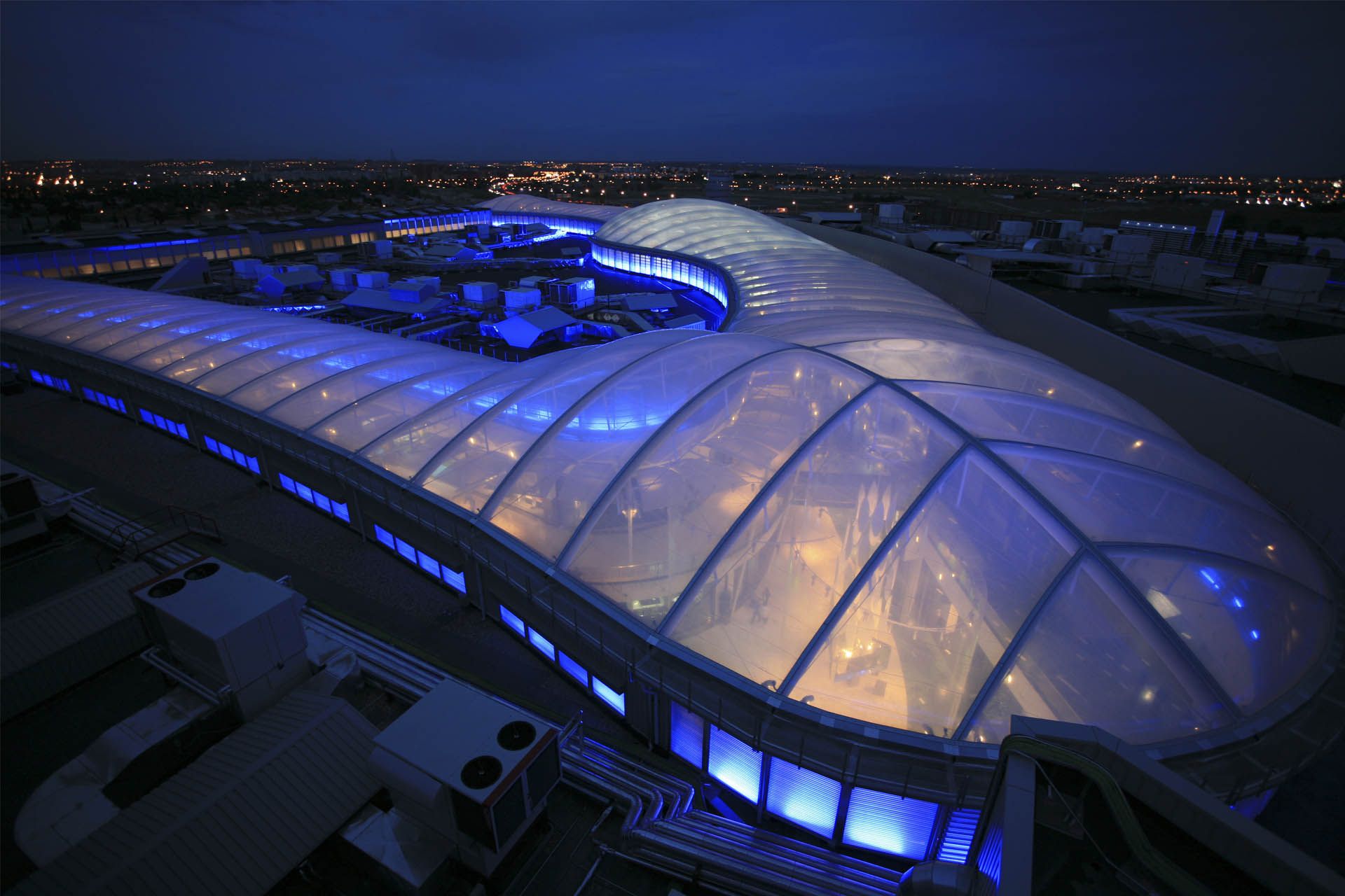 Vista aérea de la cubierta etfe transparente de noche iluminada en azul del centro comercial islazul